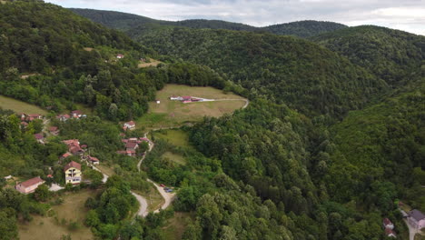 Vista-Aérea-De-Casas-En-Laderas-De-Montañas-Verdes-Y-Exuberantes,-Carro-En