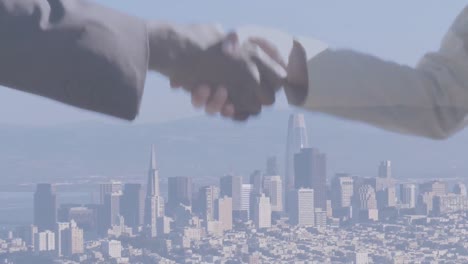 composite video of businessman and businesswoman shaking hands against aerial view of cityscape