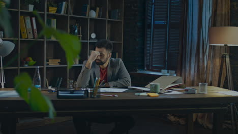 tired businessman at end of work day in home studio. tired man sitting at desk