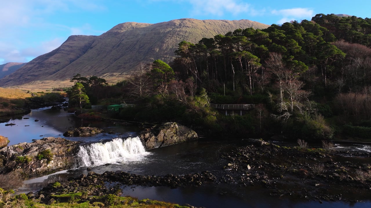 4K Aerial view of Aasleagh Falls highlighting a small waterfall along a river in a remote natural setting. Captures the movement of water and surround._10