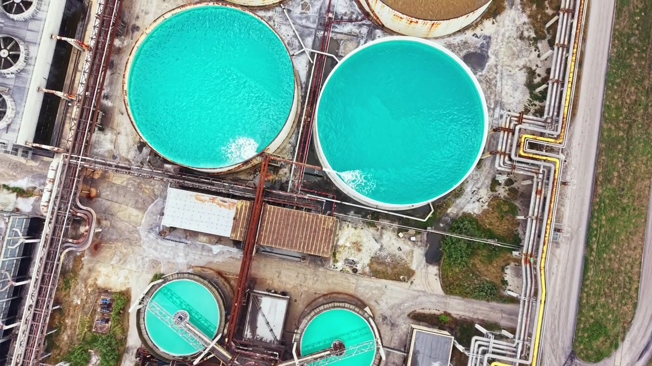 Water treatment facility in a rural area with large circular tanks and pipes during the day