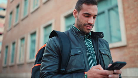 Young-man-texting-on-smartphone-outdoors.