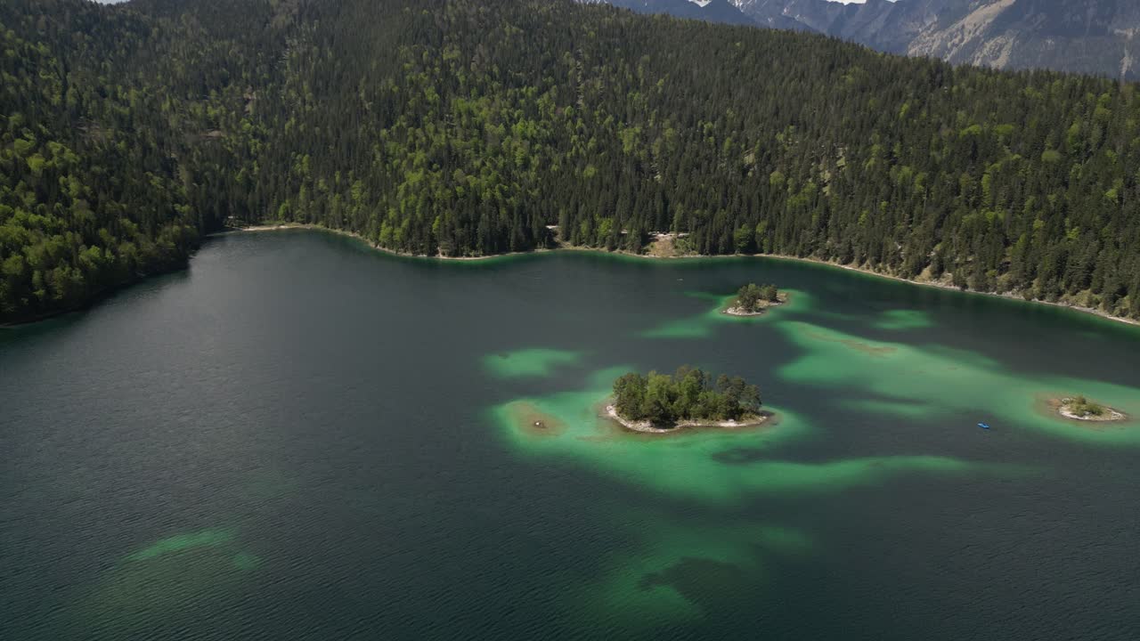 vista aérea de un lago azul rodeado de un hermoso bosque de pinos, parecido a un mundo de fantasía, con pequeñas islas en el centro del lago eibsee, baviera, alemania