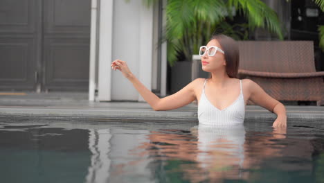 Elegante-Mujer-Exótica-Delgada-Con-Gafas-De-Sol-En-La-Piscina-Del-Complejo-Hotelero,-Marco-Completo