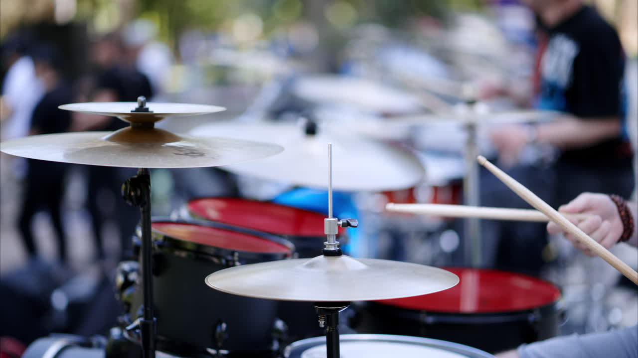 Close up of man playing red drums outside
