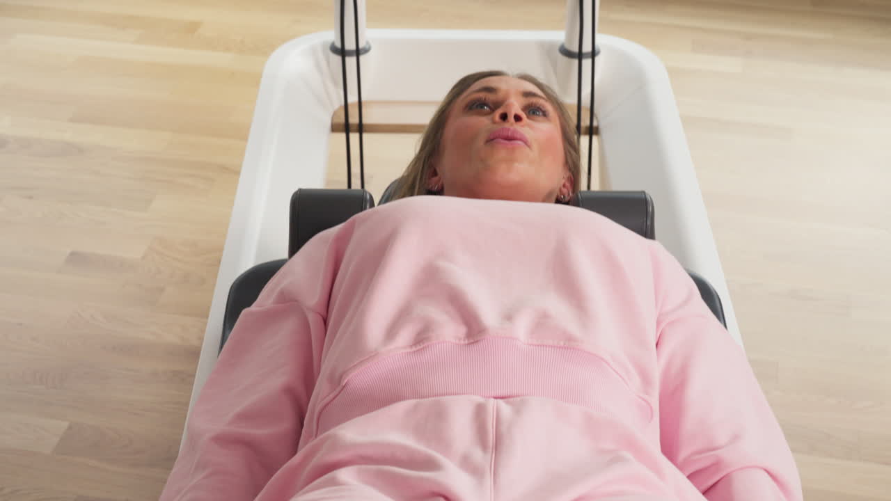 Lying Fit Athletic Woman Exercising On Pilates Reformer Machine. Tracking Shot
