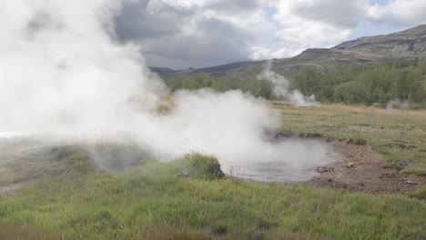 slow motion shot of boiling volcanic natural spring releasing steam in iceland