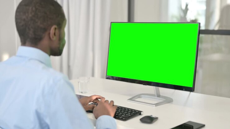 Uomo d'affari pensieroso che lavora al computer desktop con schermo Chroma Key verde