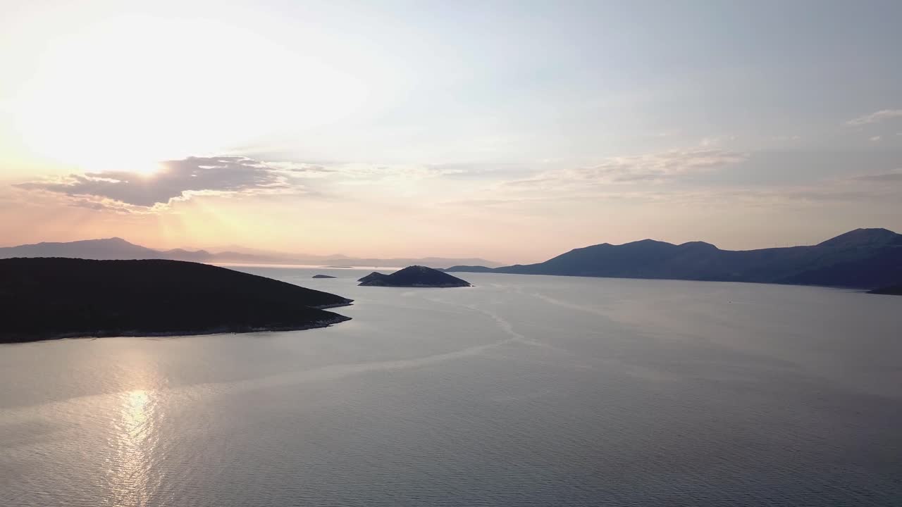 Pemandangan pulau-pulau Yunani saat matahari terbenam dengan matahari bersembunyi di balik awan.