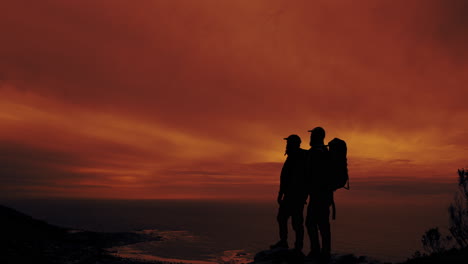 hikers silhouetted against a fiery sunset