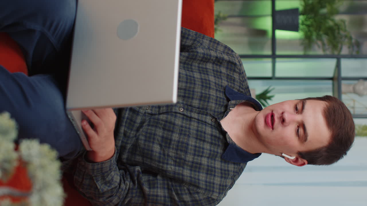 hombre sentado en el sofá de casa, mirando a la cámara, haciendo una llamada de videoconferencia con amigos o familiares