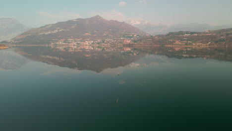 Hermoso-Paisaje-Italiano-Reflejado-En-Las-Tranquilas-Aguas-Del-Lago-En-Una-Mañana-Nublada-En-Lago-Di-Annone,-Norte-De-Italia---Toma-Aérea-De-Drones