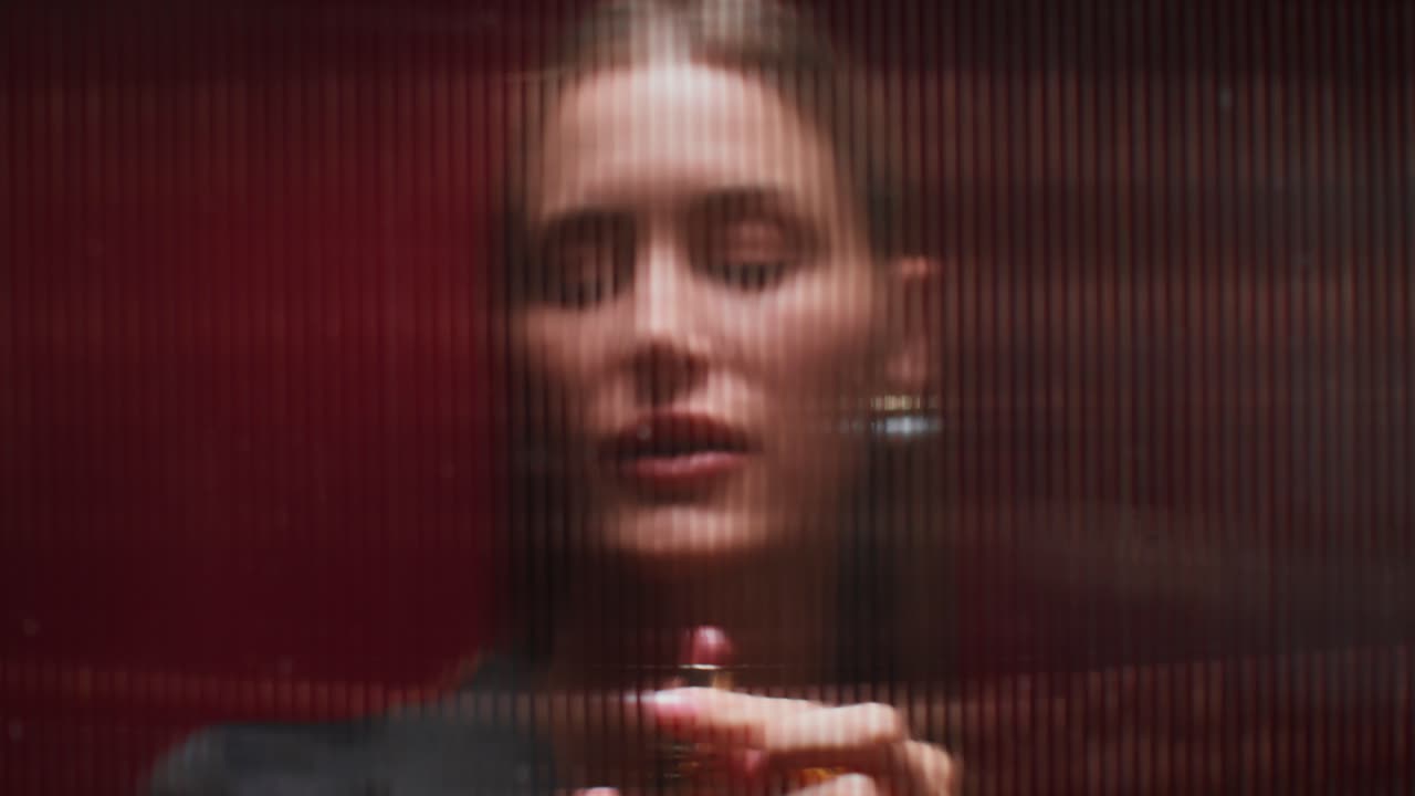 mujer aplicando lápiz labial frente a un fondo rojo