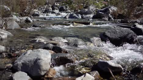 la mitad de la velocidad del agua clara que fluye a través de las rocas en un arroyo en el sur de california