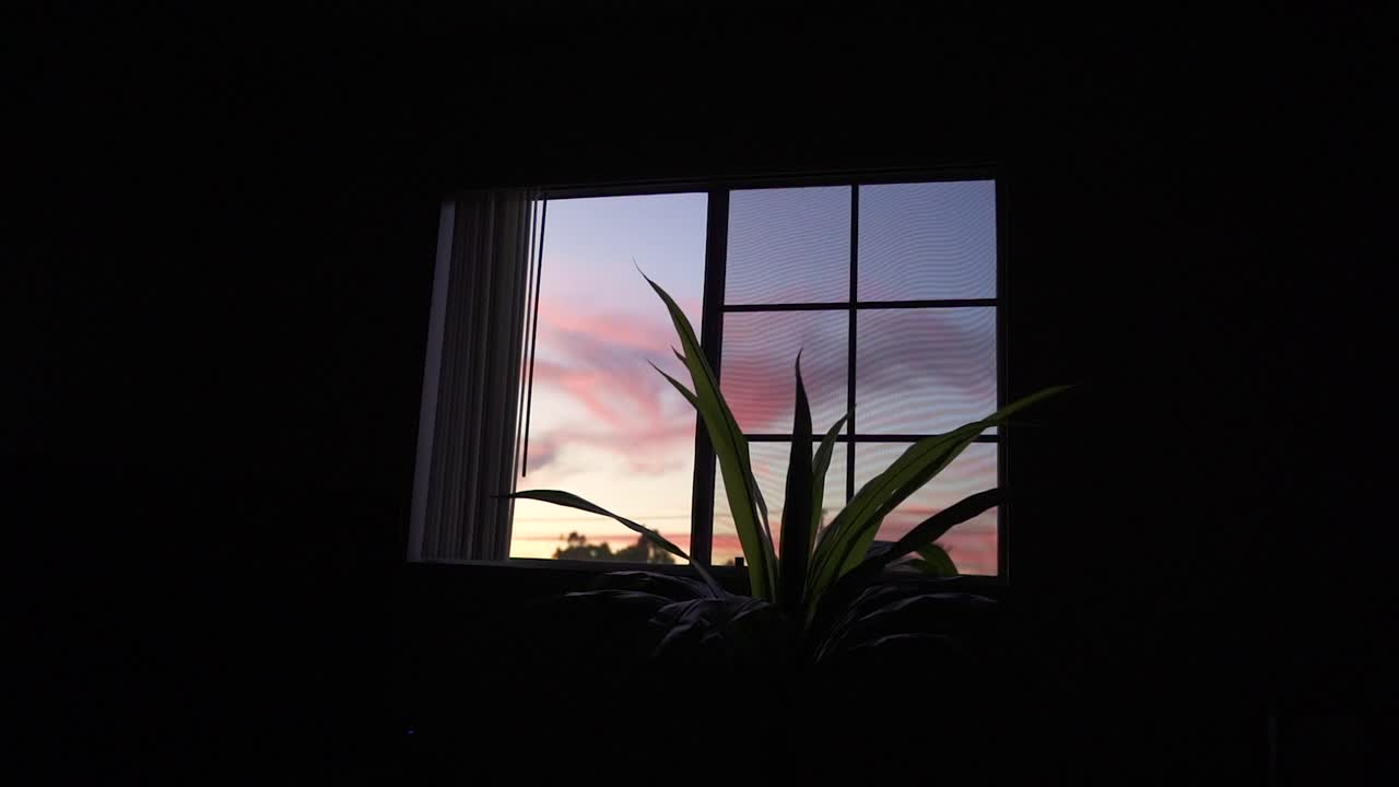 A colorful sunset viewed out the window of a third-story apartment.