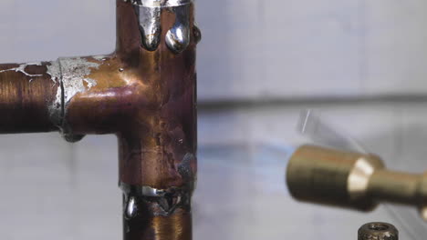 extreme closeup of a copper tee pipe being soldered during a diy home repair