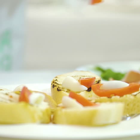 work of a professional chef for the preparation of traditional canapes. process of preparation toasts with cheese, tomato and becon on the plate in the restaurant.