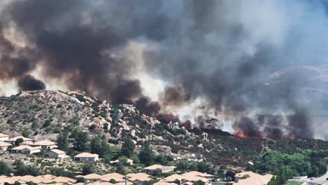 Großer-Waldbrand-In-San-Jancinto-Wildlife-Area-über-Der-Sun-Lakes-Gemeinde-In-Kalifornien,-Der-Feuer-In-Der-Nähe-Von-Häusern-Verbietet.-Telestatisches-Luftbild