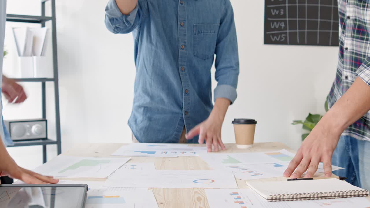 Group of young adult Asian business people join hands stacking and clap together in team meeting. Startup small business office, success teamwork celebration, happy work life concept