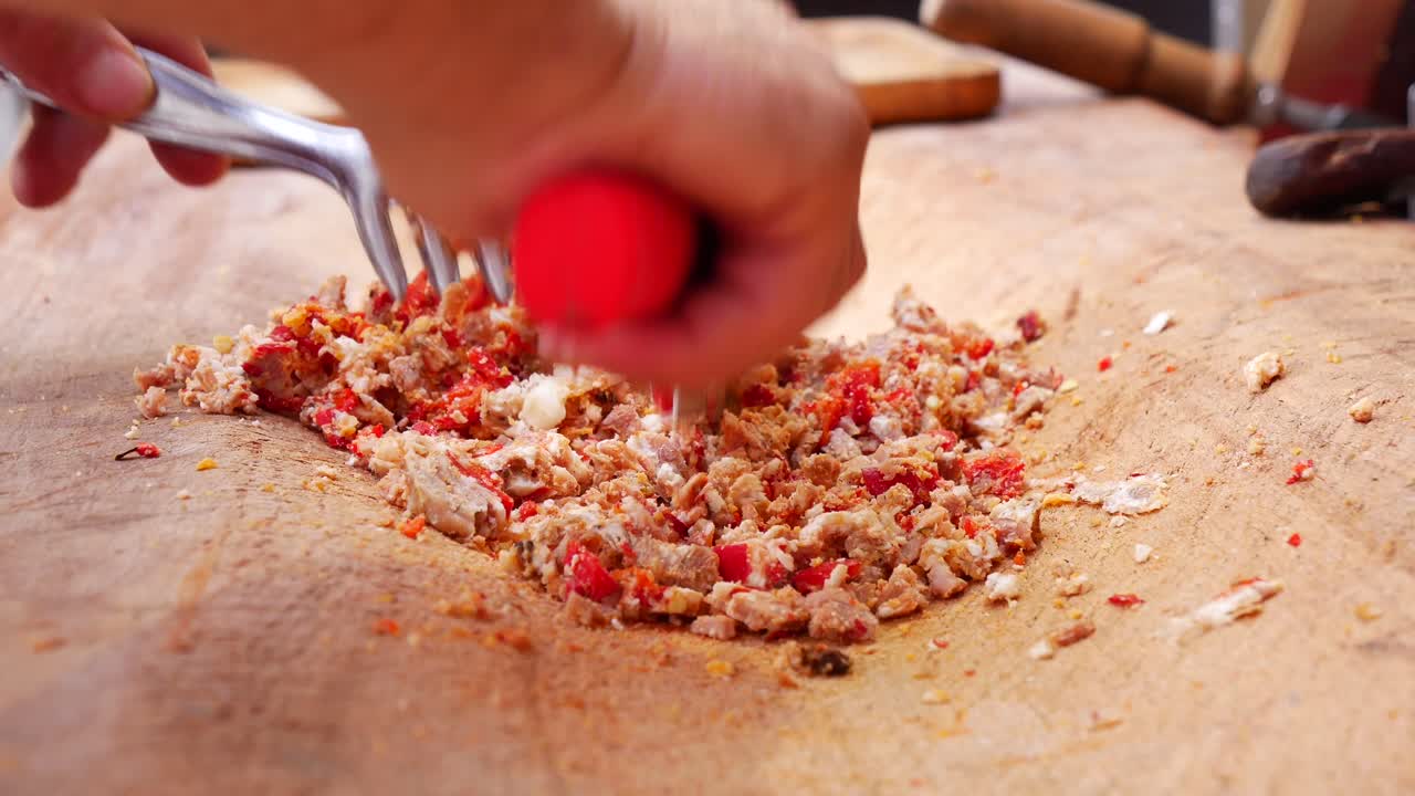 한 사람 이 칼 으로 나무판 에 고기 를 고 있다