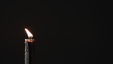 Video-of-green-candle-with-white-flame-and-copy-space-on-black-background