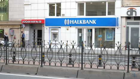 a man walks past a halkbank atm in the city