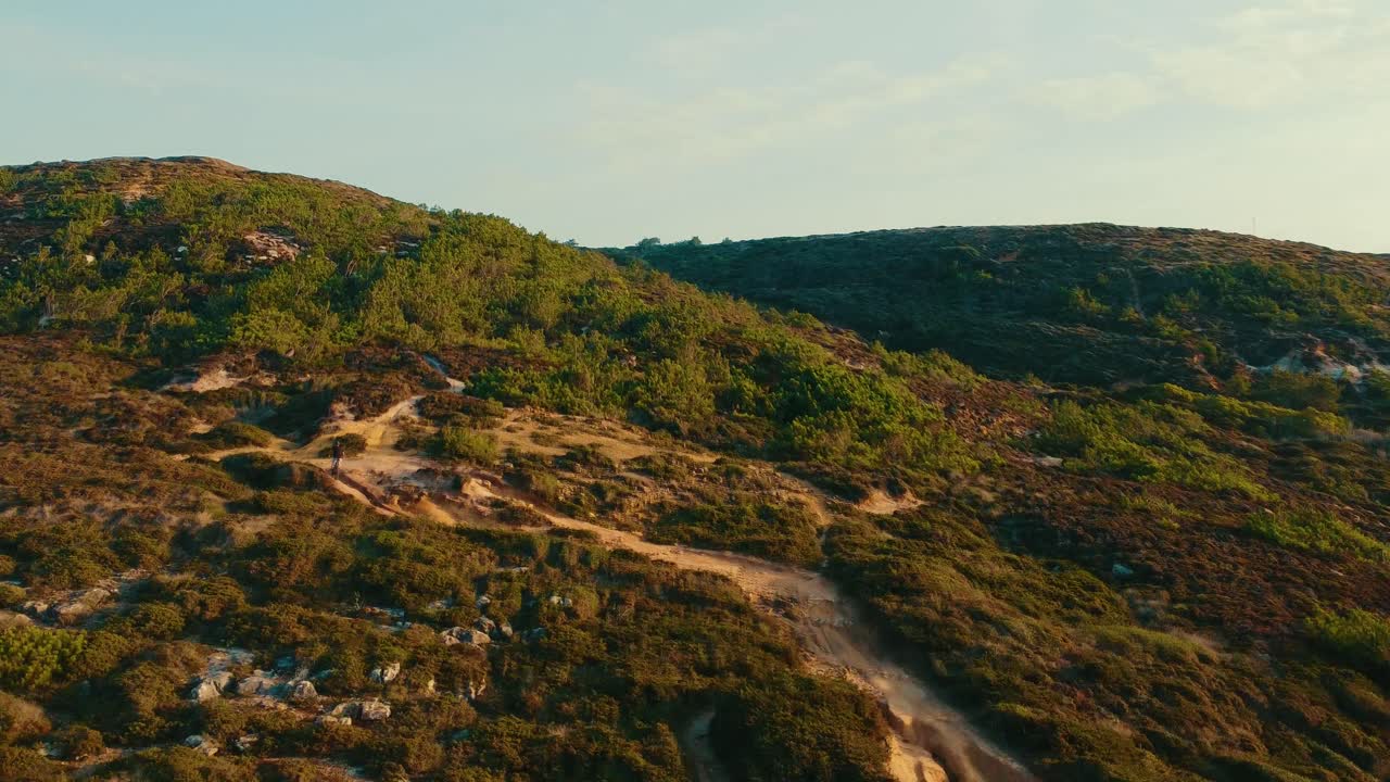 volando sobre una montaña verde mientras una persona anda en bicicleta en el corazón de la naturaleza, ericeira portugal