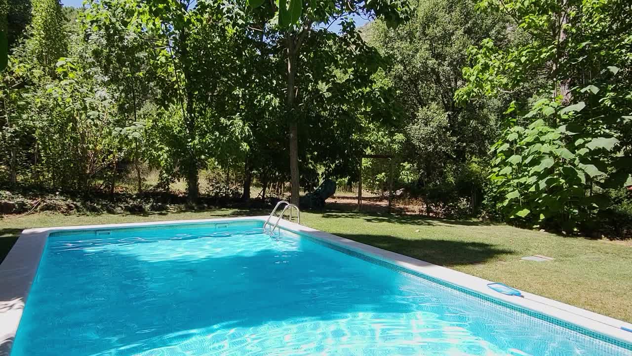 Pool mellem træerne. Farverig blå pool ved siden af skoven og græsområdet. Ferievillaer. Sommerferie. Spanien.