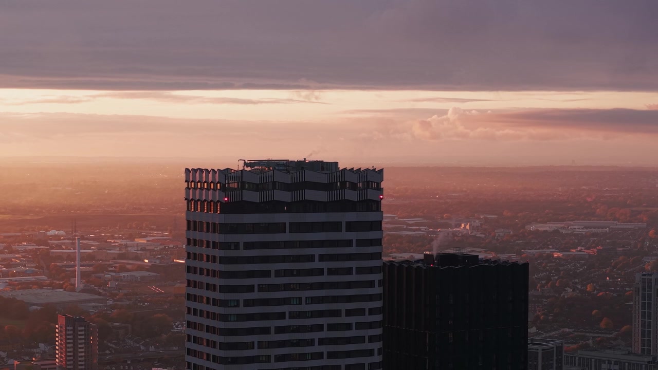 Vista aerea introduttiva che sorvola i condomini residenziali di Croydon con un paesaggio urbano dorato e velato.
