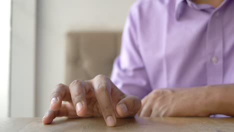 person sitting at a table with their hands on the surface