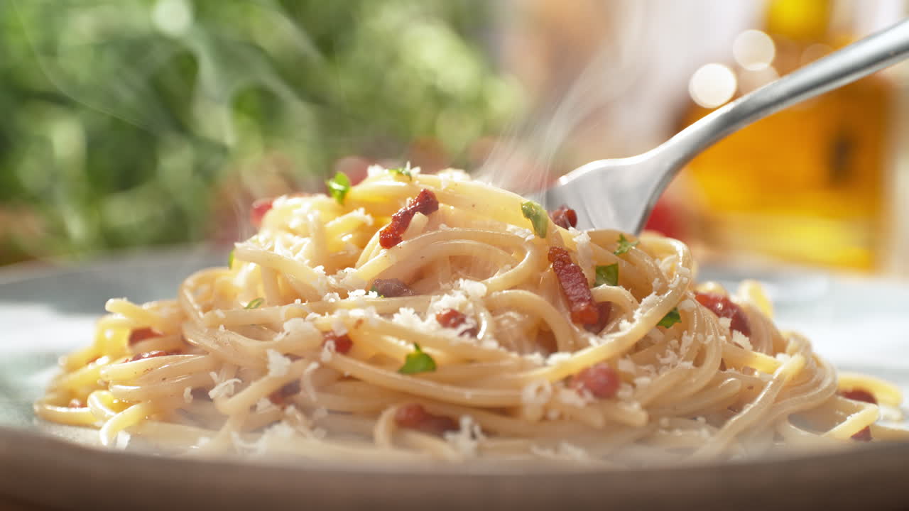 espagueti carbonara envuelto alrededor de un tenedor - desde una vista del plato en el plato hasta un primer plano de las hebras de pasta en el utensilio de plata