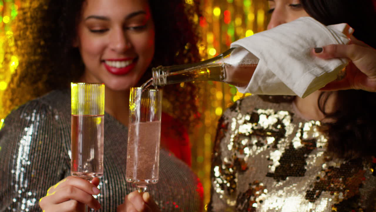 Close Up Of Two Women In Nightclub Bar Or Disco Having Champagne Poured From Bottle
