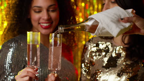 cerca de dos mujeres en un bar de club nocturno o discoteca con champán vertido de la botella