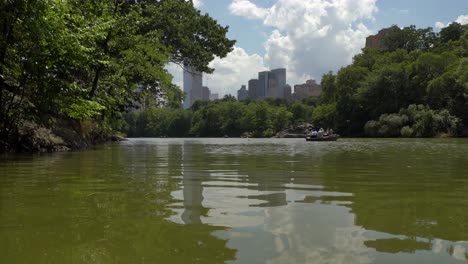 Botes-De-Remos-En-El-Parque-Central-Contra-Un-Fondo-Del-Horizonte-De-La-Ciudad-De-Nueva-York