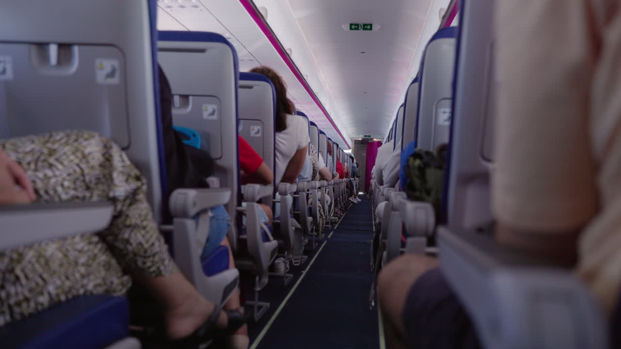 Vista del pasillo de la cabina de un avión con pasajeros sentados.