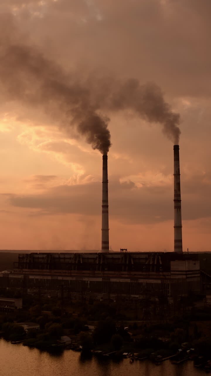 High voltage post. High-voltage tower sky background, factory pipe with smoke over it. Earth pollution and industrialization concept. Selective focus. Vertical video