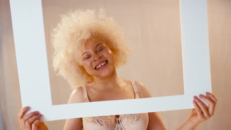 studio shot of confident natural woman in underwear promoting body positivity in picture frame