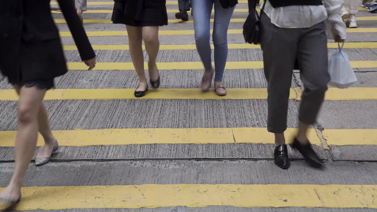 Pedestrians walk across the road through a zebra crossing in Central district, Hong Kong.