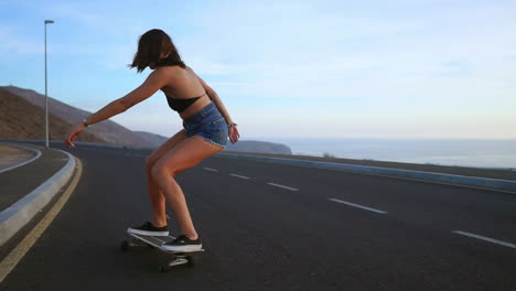 young ginsana skateboards on the road against a backdrop of great mountains and sky