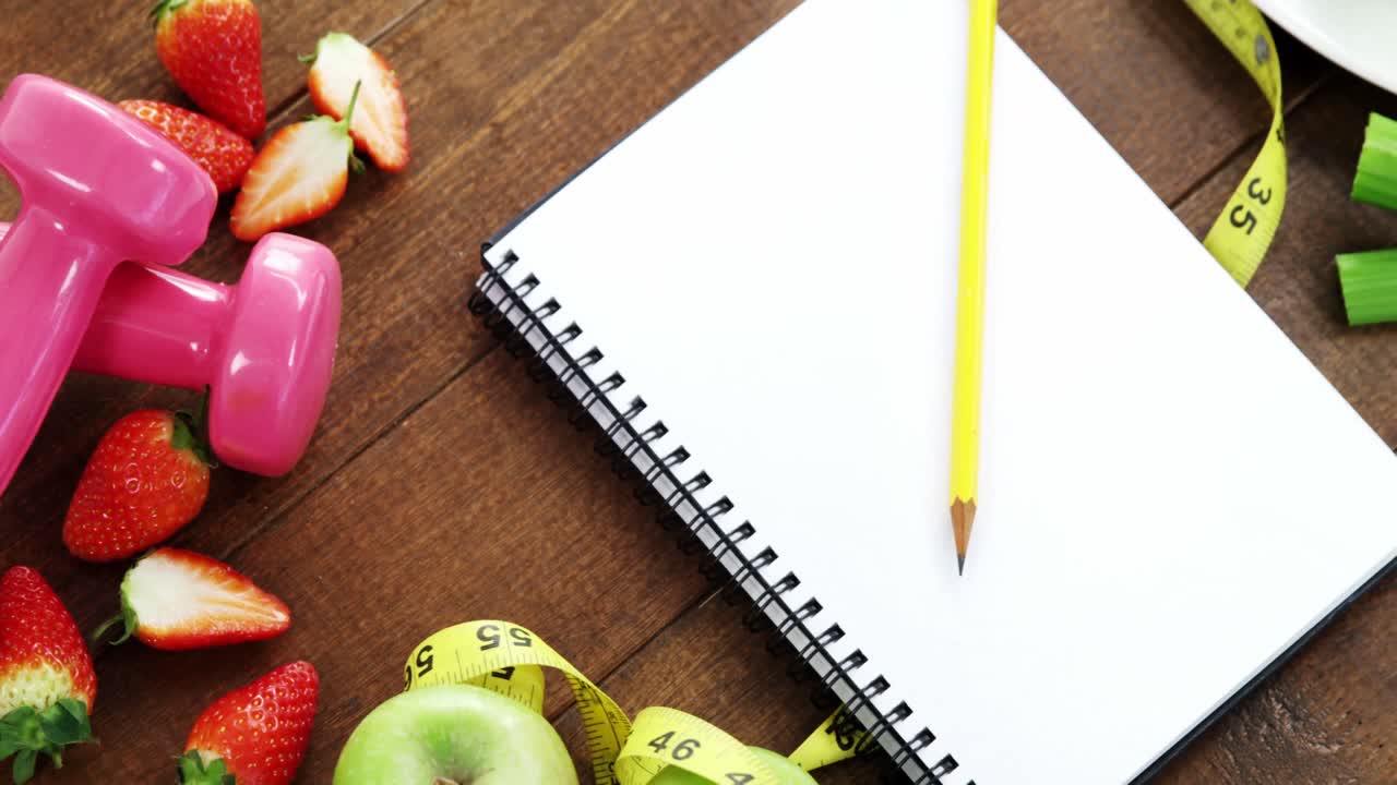 fresa, cinta métrica, pesas y cuaderno en espiral en la mesa