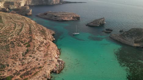 Vista-Aérea-De-Drones-Inclinados-Hacia-Abajo-De-La-Magnífica-Laguna-Azul-De-Malta,-Famosa-Por-Sus-Fascinantes-Aguas-Claras