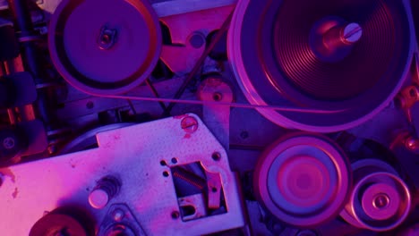 close-up of vintage tape recorder mechanism under neon light