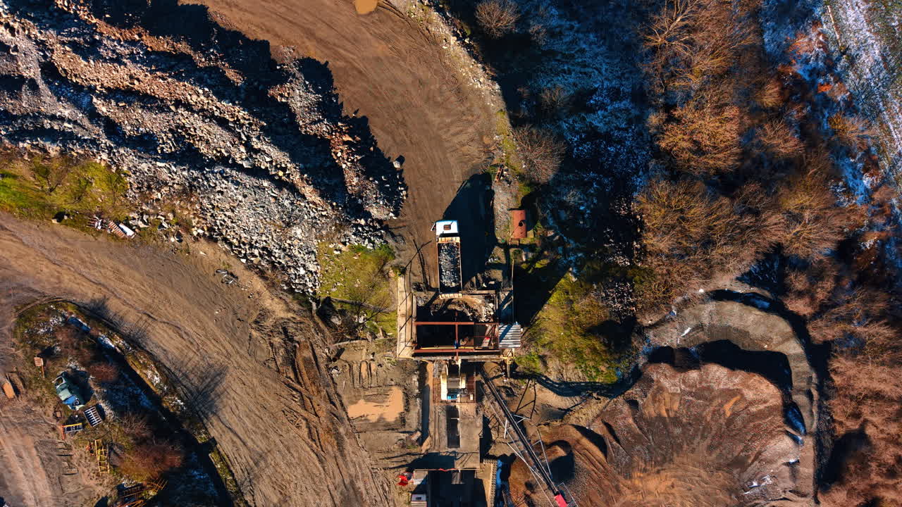 Top view of primary stone crusher at granite quarry. Aerial top down view of a heavy industrial crusher processing raw granite stones in a quarry