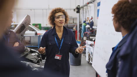 Female-Tutor-By-Whiteboard-With-Students-Teaching-Auto-Mechanic-Apprenticeship-At-College