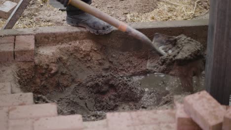 construction workers use shovels to apply cement mixture to building support pillars