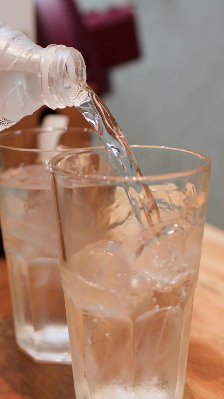 Primo Piano di Acqua Fresca Versata da una Bottiglia in un Bicchiere Ghiacciato