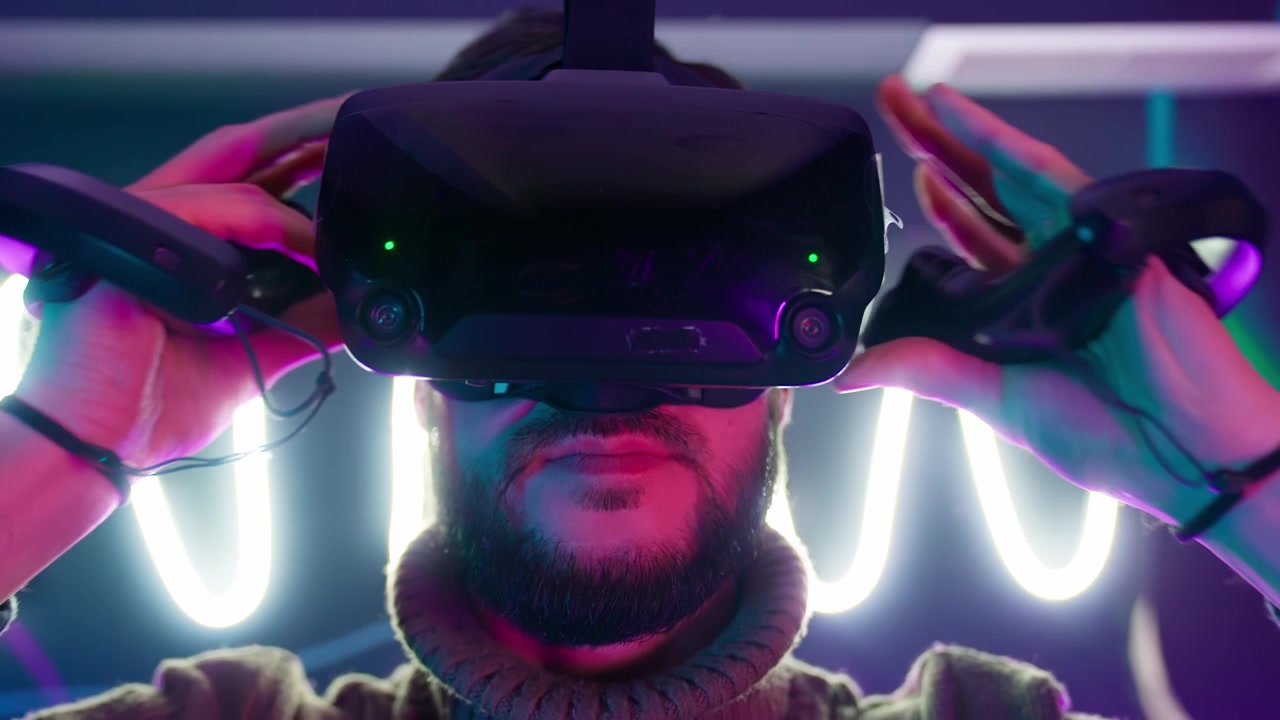 Bearded Man Puts on VR Headset in a Neon Lit Room