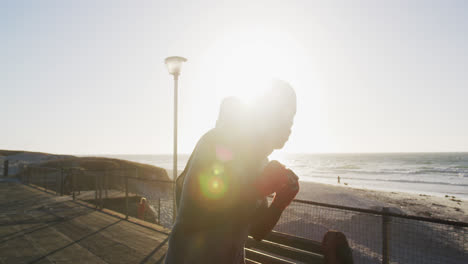 Focused-african-american-man-boxing-and-running,-exercising-outdoors-by-the-sea