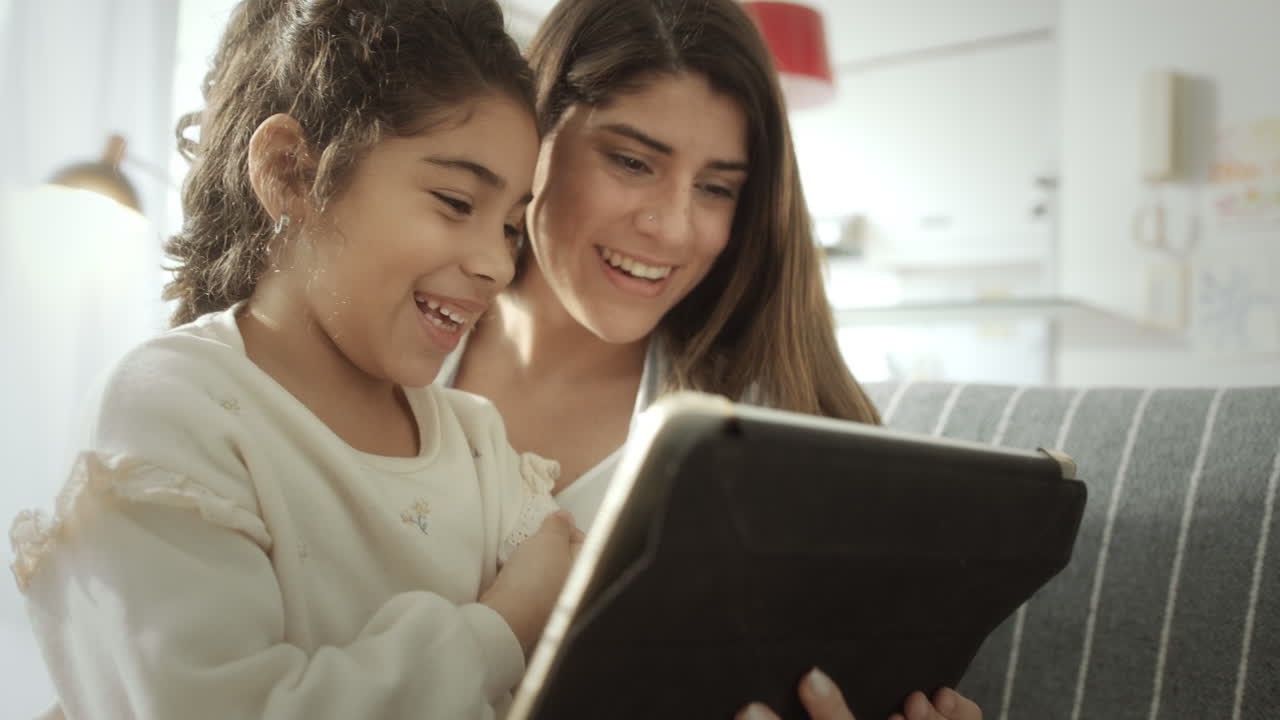 Loving Mom and Little Daughter Using Digital Tablet at Home