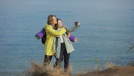 traveler couple smiling and posing taking selfie using smartphone standing on top of the cliff